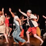 Une scène de théâtre animée avec un groupe de personnes en train de danser.
