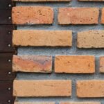 Mur en briques rouges avec planche en bois sombre et vis métalliques