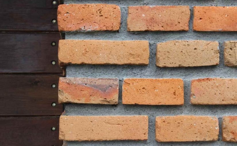 Mur en briques rouges avec planche en bois sombre et vis métalliques