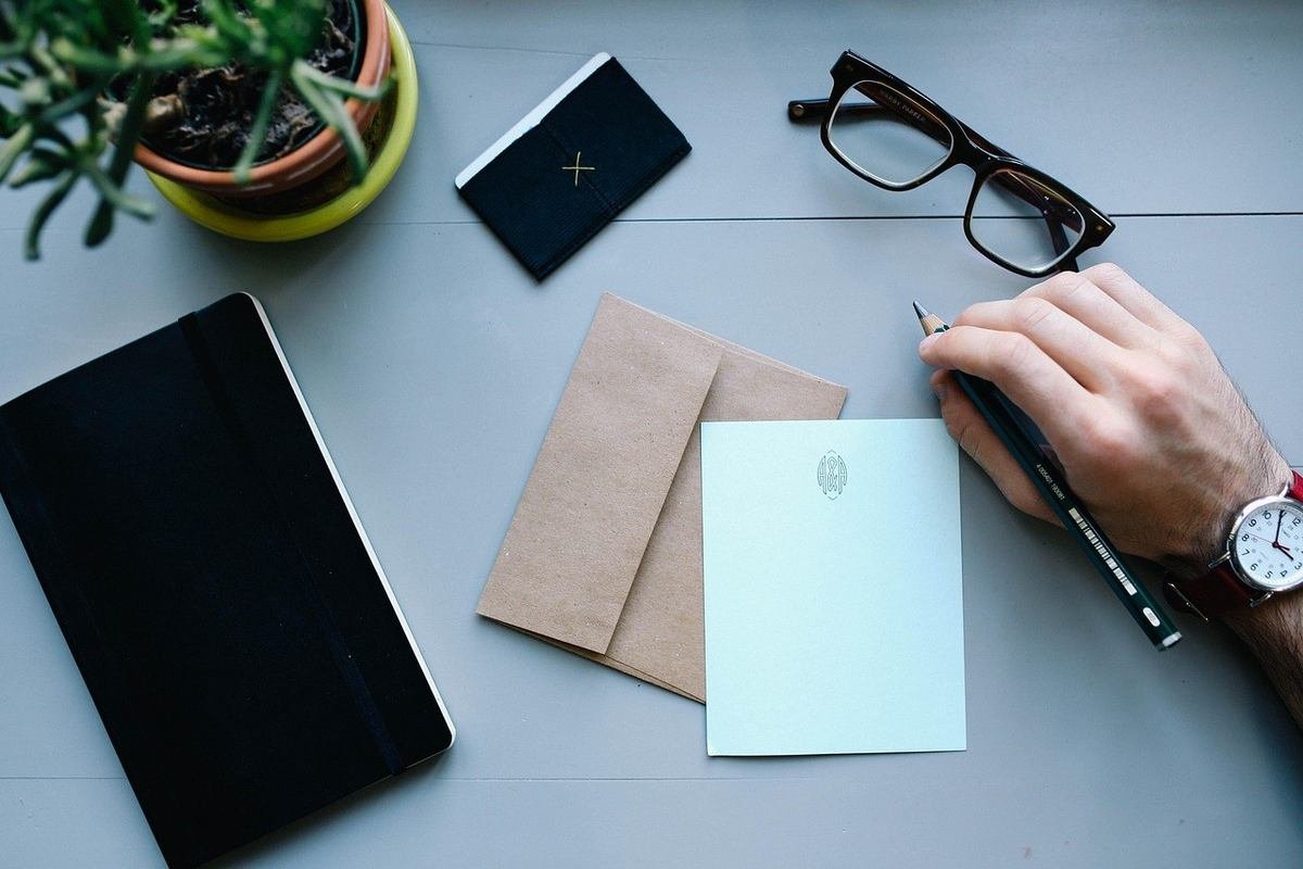 Main tenant un stylo au-dessus d'une carte blanche sur une table