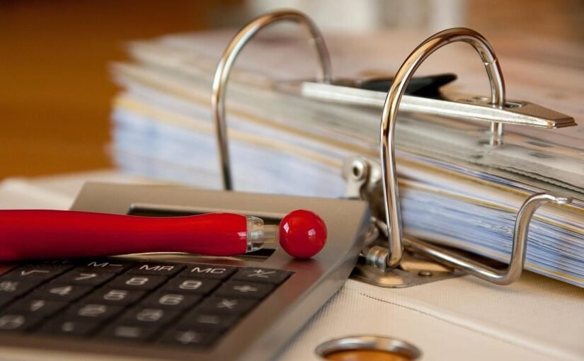 Calculatrice, stylo rouge et classeur à anneaux sur un bureau de travail administratif