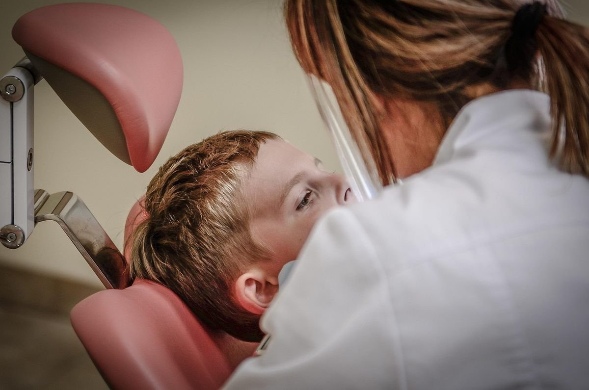 Dentiste inspecte la bouche d'un enfant dans un cabinet dentaire