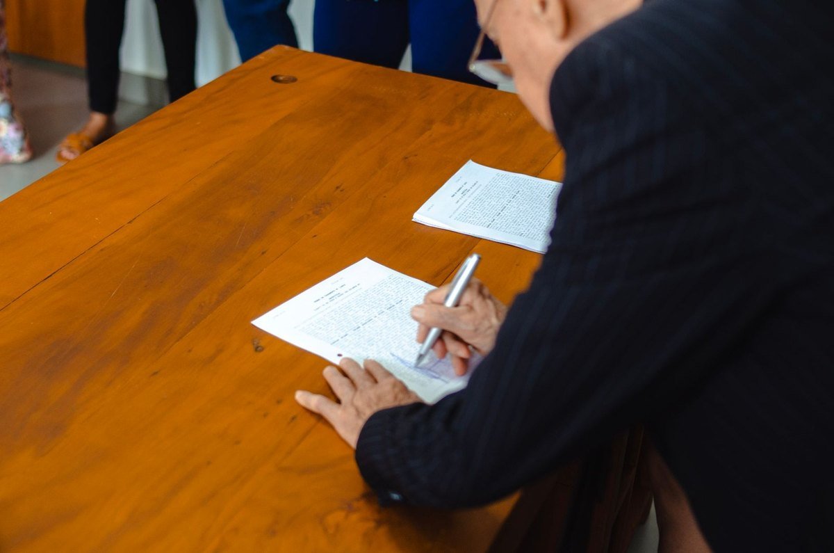 Homme en noir écrivant sur une feuille à la table en bois Homme en noir écrivant sur une feuille à la table en bois
