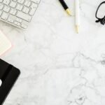 Clavier, notes, téléphone, ciseaux et stylos sur une surface marbrée