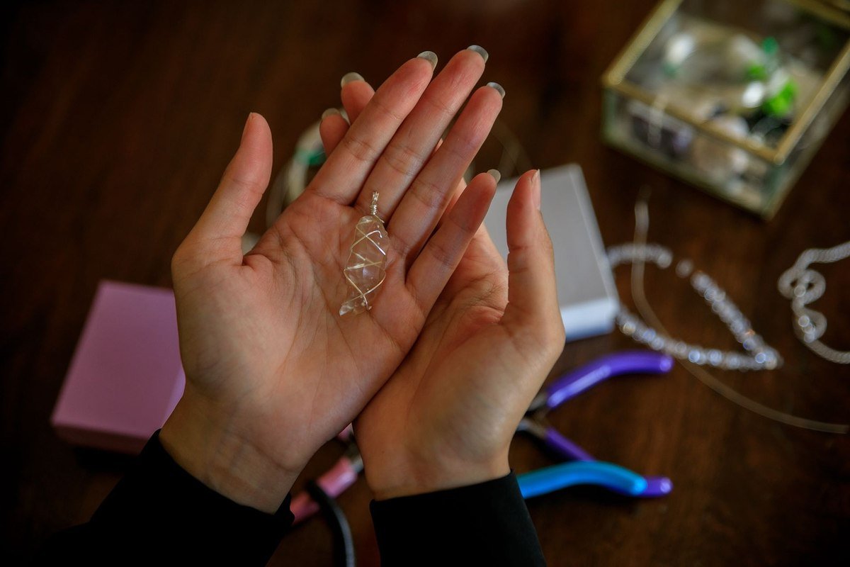 Des mains tiennent un pendentif en fil sur une table avec outils Des mains tiennent un pendentif en fil sur une table avec outils