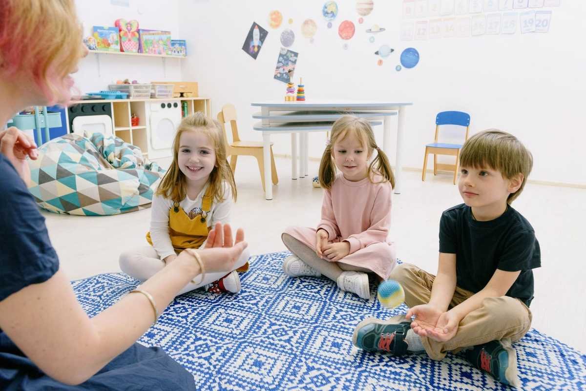 Enfants et adultes assis sur un tapis, jouant avec des objets dans une salle de classe