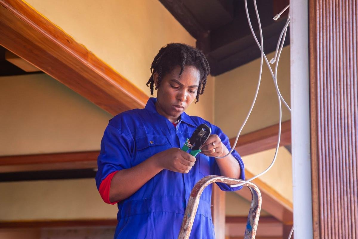Homme en bleu utilise un outil électrique près d'une échelle dans un intérieur Homme en bleu utilise un outil électrique près d'une échelle dans un intérieur