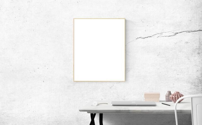 Bureau avec ordinateur et objets, tableau vide, mur texturé