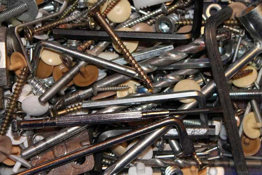 Assortiment de vis, boulons et écrous métalliques éparpillés sur une surface beige Assortiment de vis, boulons et écrous métalliques éparpillés sur une surface beige