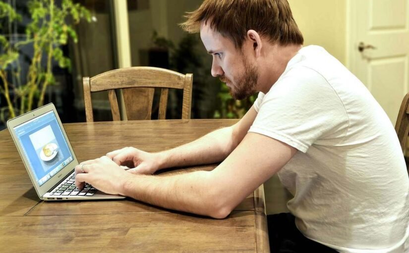 Homme travaillant sur un ordinateur portable à un bureau en bois