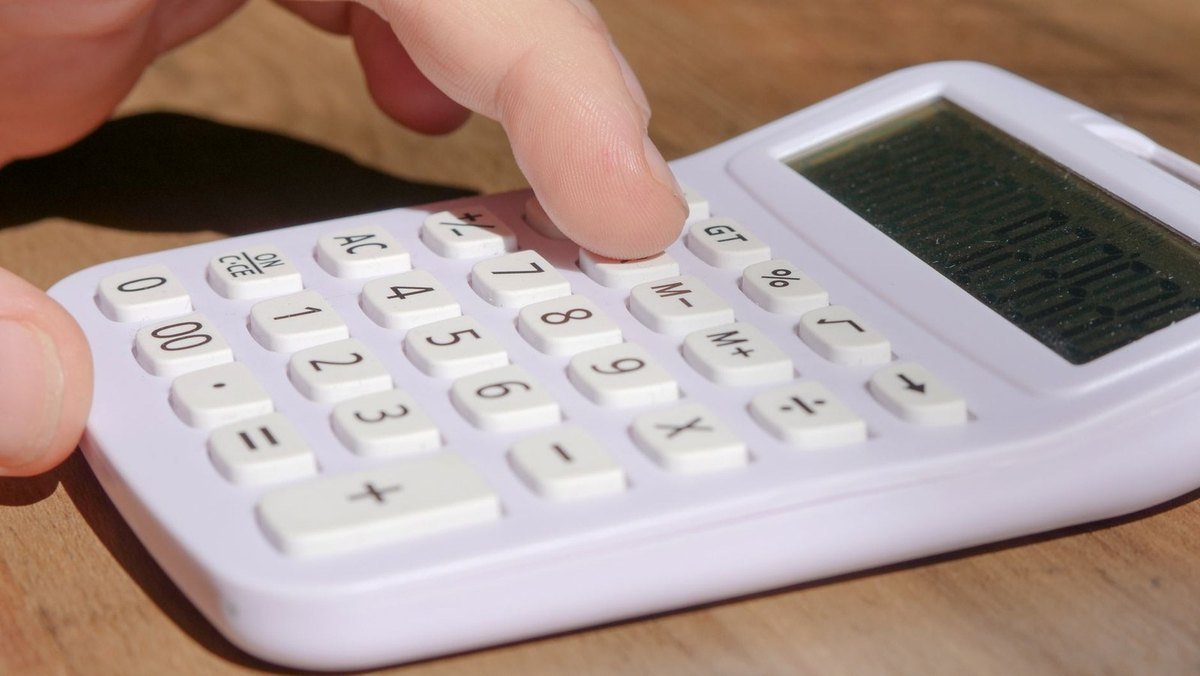 Main appuie sur bouton de calculatrice, chiffres et symboles en relief, écran vide