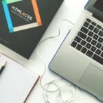Espace de travail montrant un ordinateur portable, carnet de notes, souris et écouteurs filaires