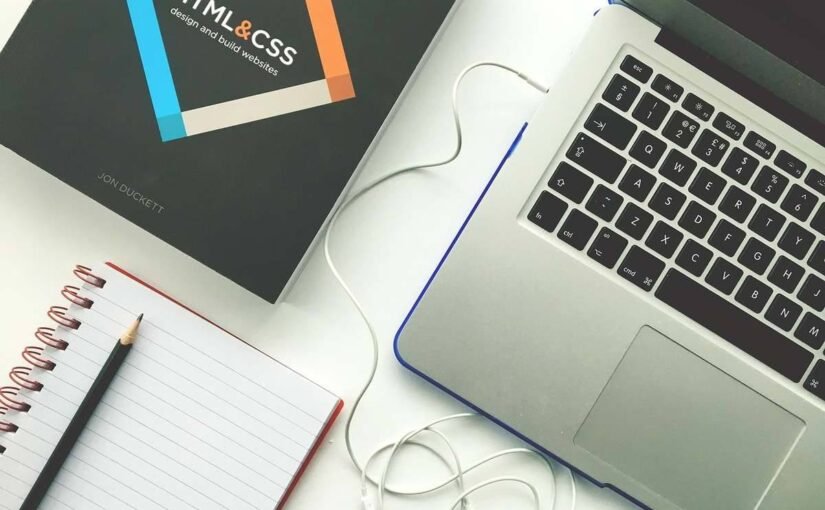 Espace de travail montrant un ordinateur portable, carnet de notes, souris et écouteurs filaires