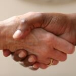 Deux personnes effectuant une poignée de main cordiale sur fond neutre beige