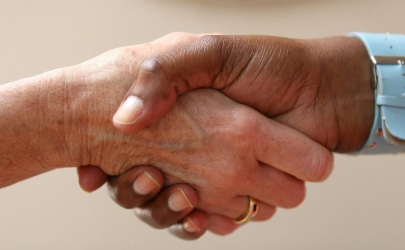 Deux personnes effectuant une poignée de main cordiale sur fond neutre beige