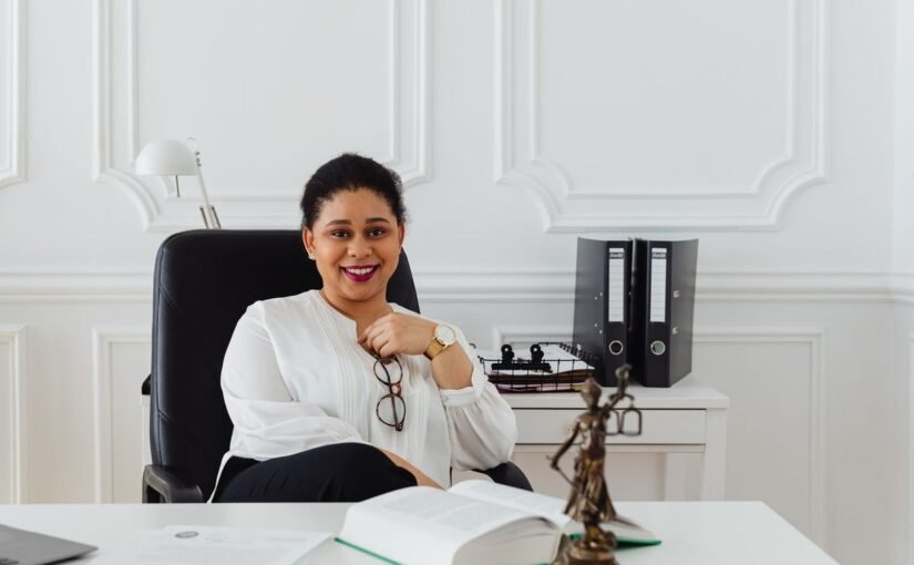 Femme souriante dans un bureau, devant un bureau avec livre et statue