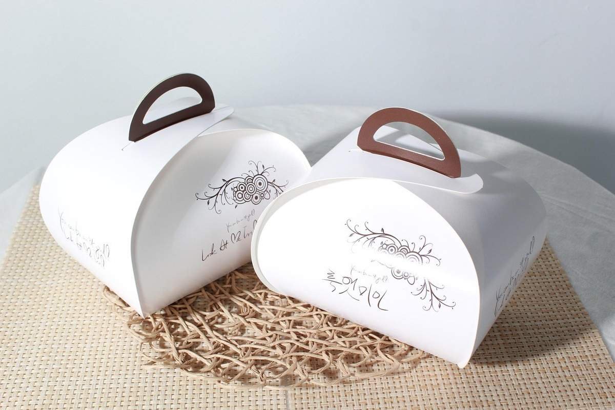 Boîtes blanches ornées de motifs floraux et poignées brunes sur un tapis tressé