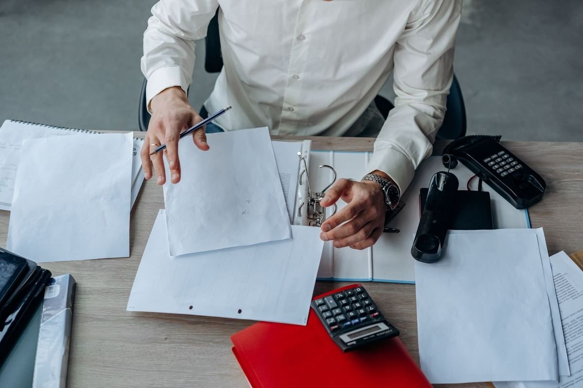 Un homme en chemise blanche examine des documents sur un bureau