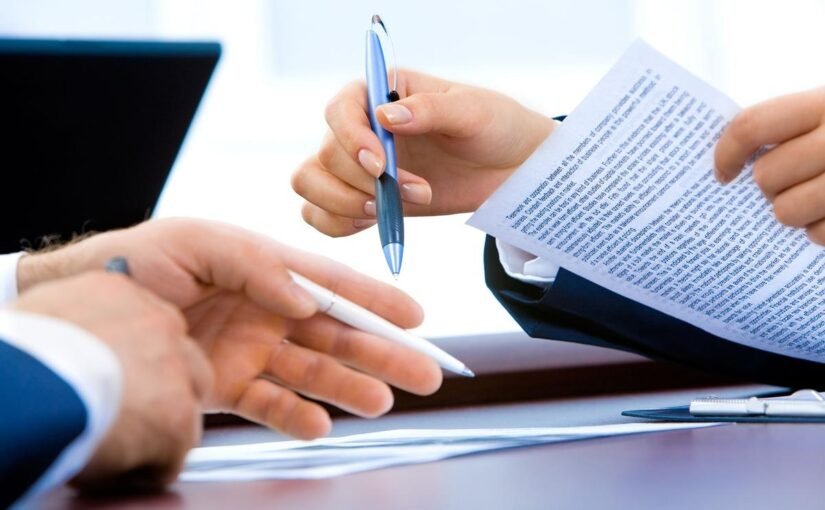 Des mains tiennent des stylos et des papiers sur une table