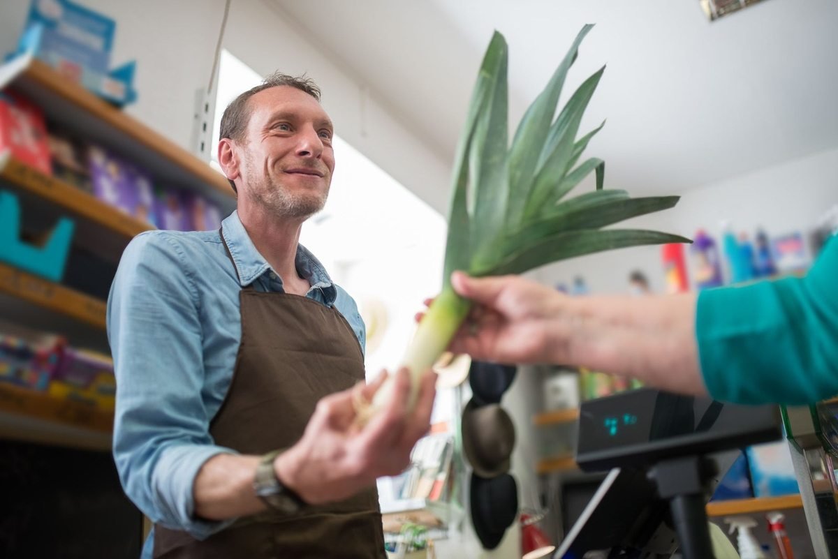 Homme recevant une plante à feuilles larges dans un magasin Homme recevant une plante à feuilles larges dans un magasin