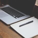 Un ordinateur portable et un cahier avec un stylo sur une table