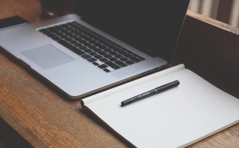 Un ordinateur portable et un cahier avec un stylo sur une table